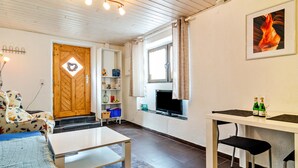 A furnished room with a bed, a table, a TV, and a window.