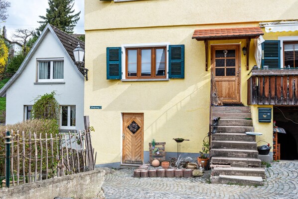 A building with a wooden door, a window with shutters, and a staircase leading to the entrance.