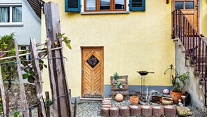 A courtyard with a wooden door, potted plants, and a cobblestone floor.