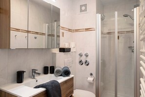 A modern bathroom with a glass-enclosed shower, a white sink, and a mirror above the vanity. - Apartment "Almzeit" with Balcony & Wi-Fi (Farchant)