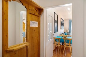 A wooden door with a sign, a dining area with blue tablecloths, and framed pictures on the wall.