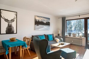 Ein modernes Wohnzimmer mit einer Couch, einem Esstisch mit Stühlen, einem Couchtisch und Kunstwerken an den Wänden.