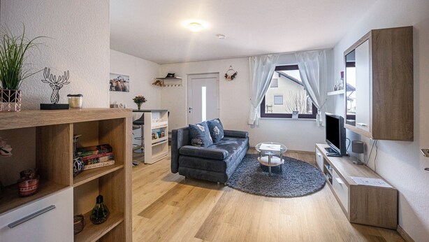 Een moderne woonkamer met een bank, televisie en een klein bijzettafeltje.