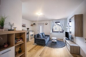 Een moderne woonkamer met een bank, televisie en een klein bijzettafeltje.