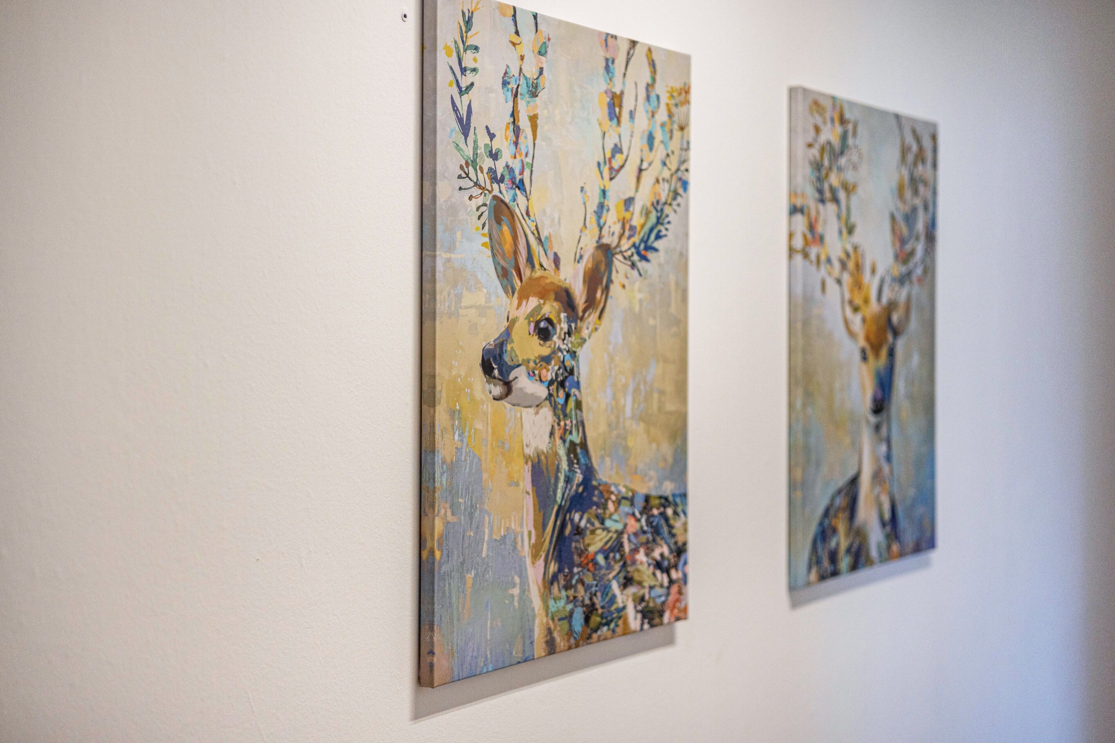 Deux tableaux représentant des cerfs sur un mur blanc.