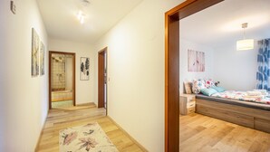 Een slaapkamer met een bed, houten vloer en een gang naar een badkamer.