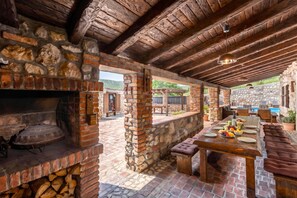 A rustic outdoor kitchen with a brick oven, stone walls, and a dining area with a table set for a meal. - Villa Cupido With Private Pool, Drivenik, Croatia (Drivenik)