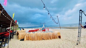 A beachside dining setup with tables and chairs, string lights, and flags. - Peace Resort (Mui Ne)