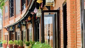 A traditional building with brick walls, multiple windows, and hanging decorative lanterns. - Peace Resort (Mui Ne)