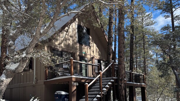 A cabin with a wooden exterior, a balcony, and a staircase leading to the entrance. - Family-sized, quaint cabin on the edge of the US Forest (Strawberry)