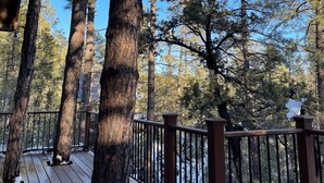 A wooden deck with a railing, surrounded by tall pine trees. - Family-sized, quaint cabin on the edge of the US Forest (Strawberry)