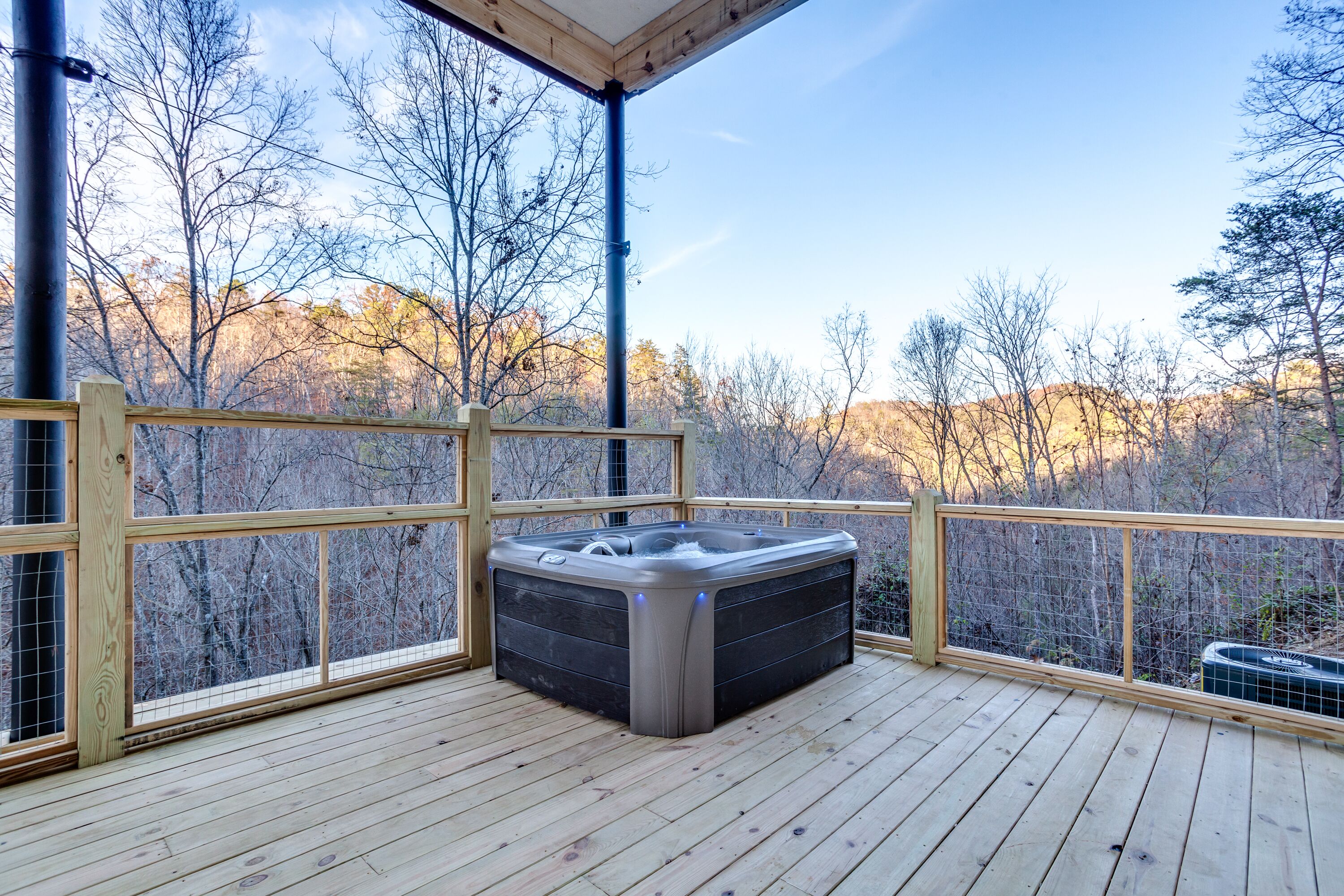 A hot tub on a wooden deck with a view of a forested area.