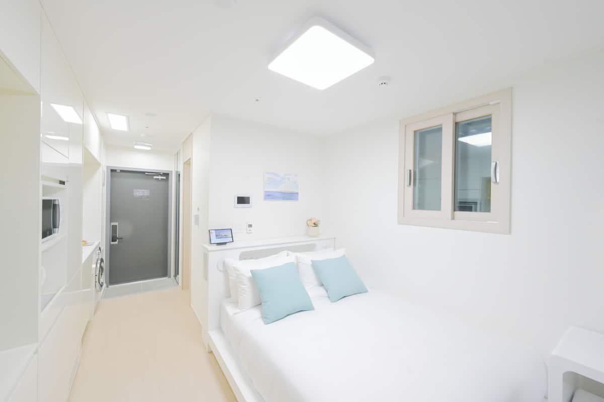 Une chambre d’hôtel moderne avec un lit, une table de chevet et une petite fenêtre.