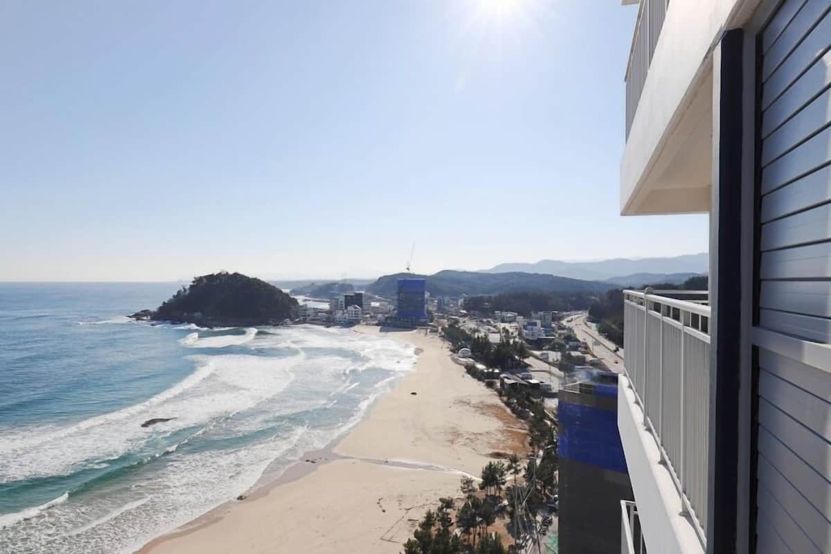 Une vue côtière avec une plage, l’océan et des montagnes à l’horizon.