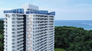 Ein Hochhaus mit mehreren Balkonen und freiem Blick auf das Meer, mit einem Schild, das den Namen oder einen Bereich des Gebäudes angibt.
