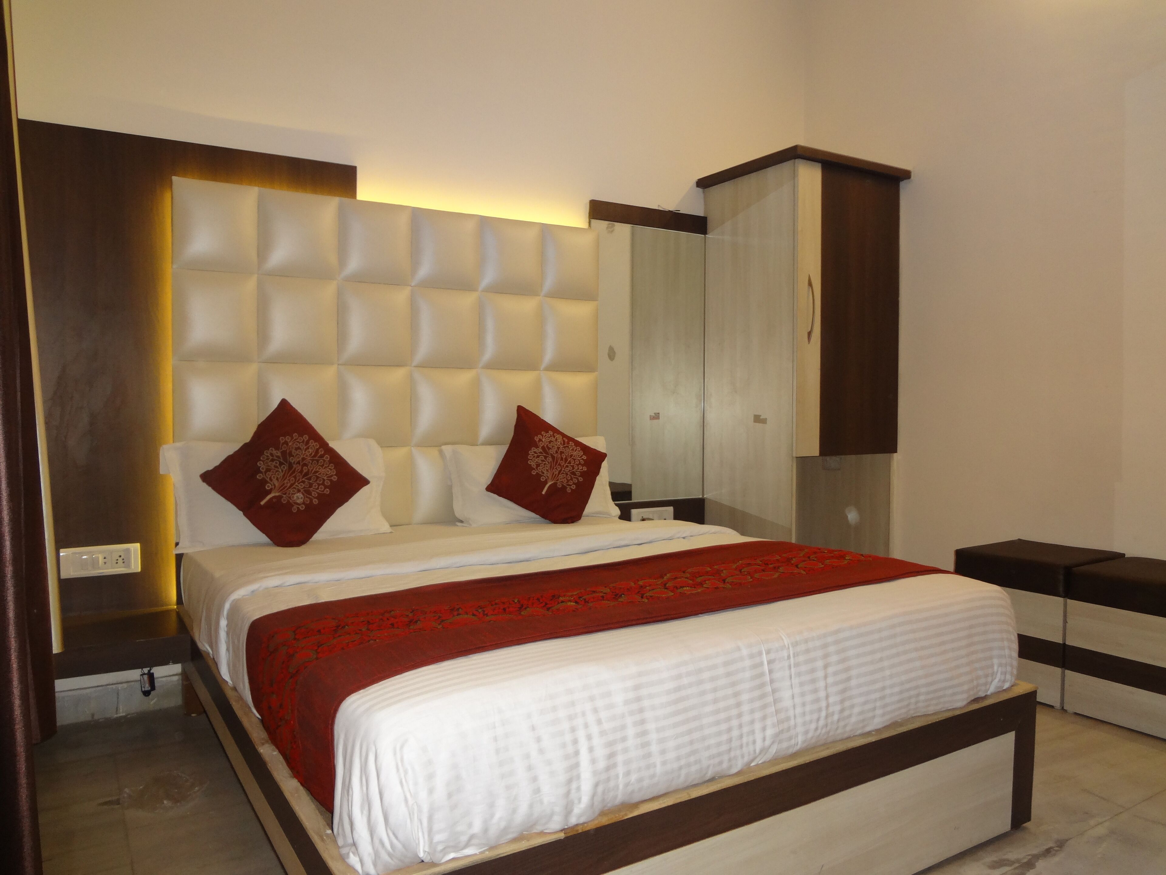 A neatly made bed with a red and white bedspread, a tufted headboard, and two decorative pillows.