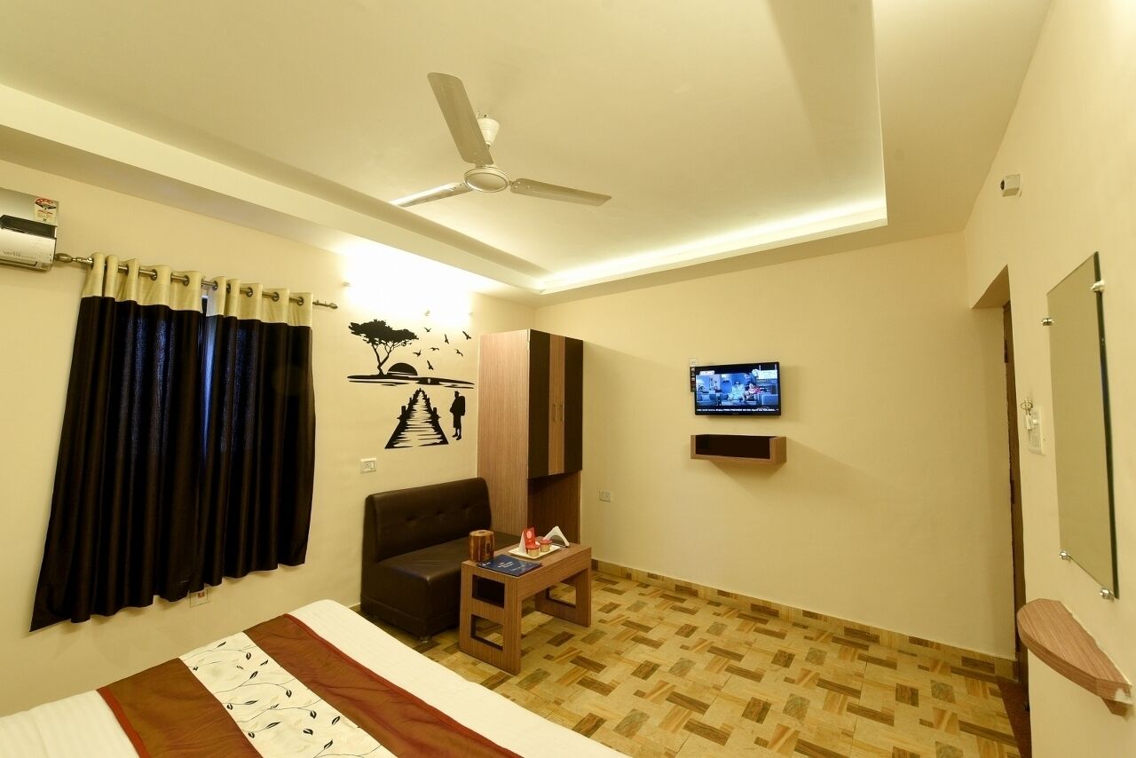 A hotel room with a bed, a ceiling fan, a TV, a small table, and a sofa.