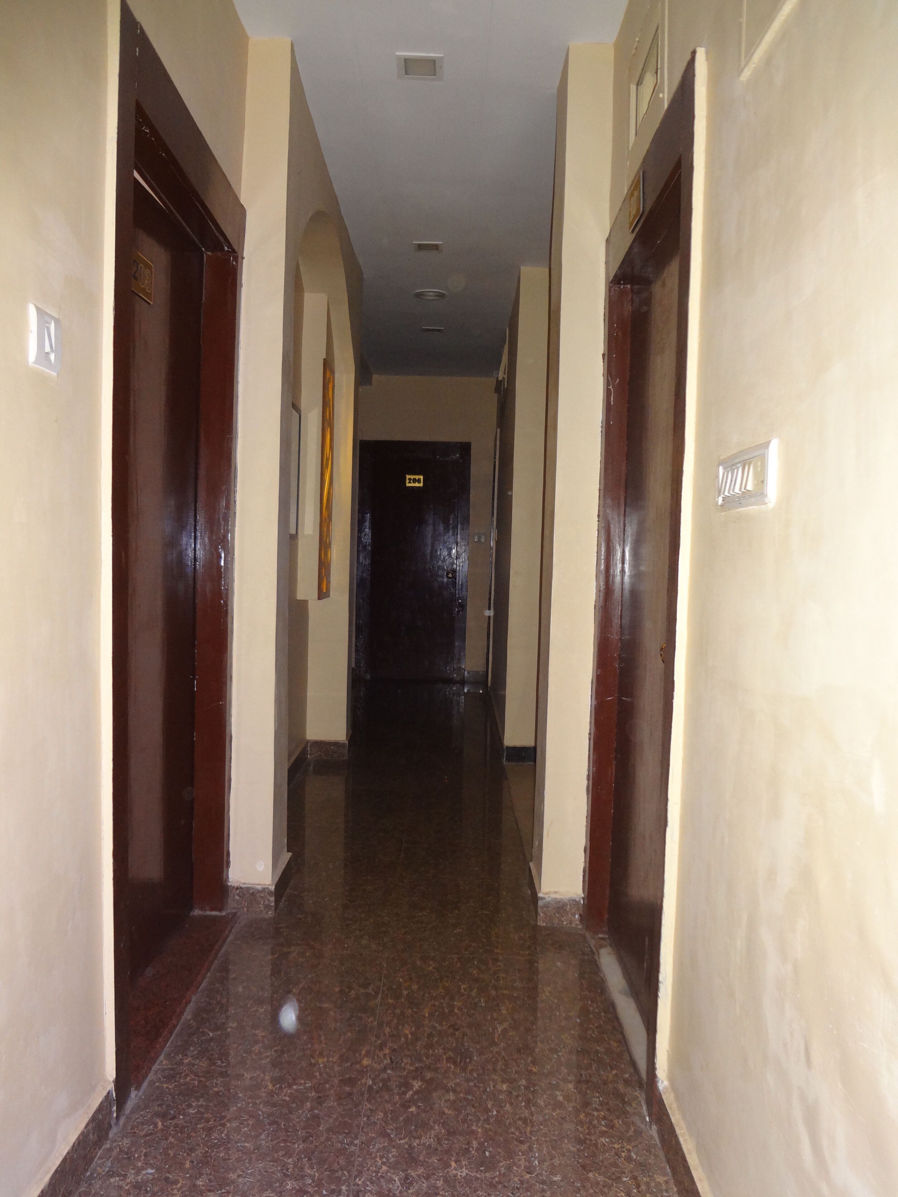 A hallway with doors on both sides, numbered 200 and 201, leading to rooms. The floor is tiled, and the walls are painted a light color.