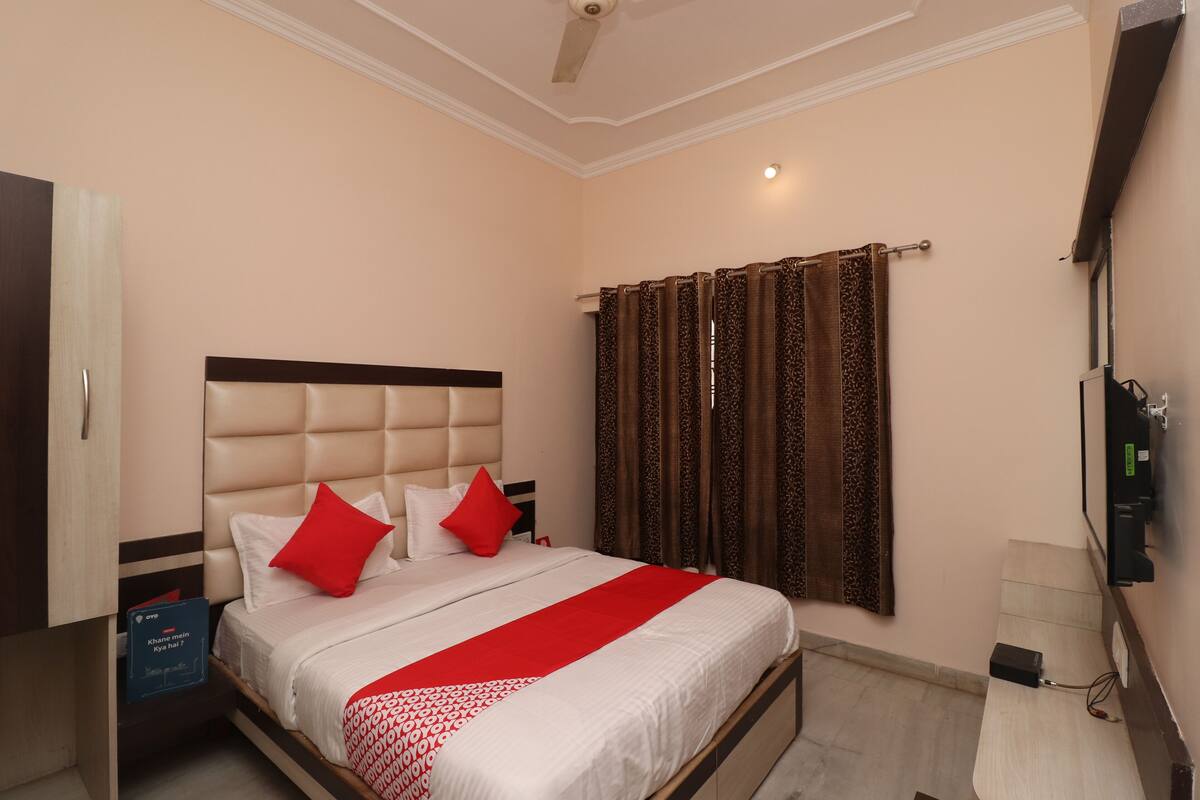 A bedroom with a bed, a wardrobe, a bedside table, and a TV.