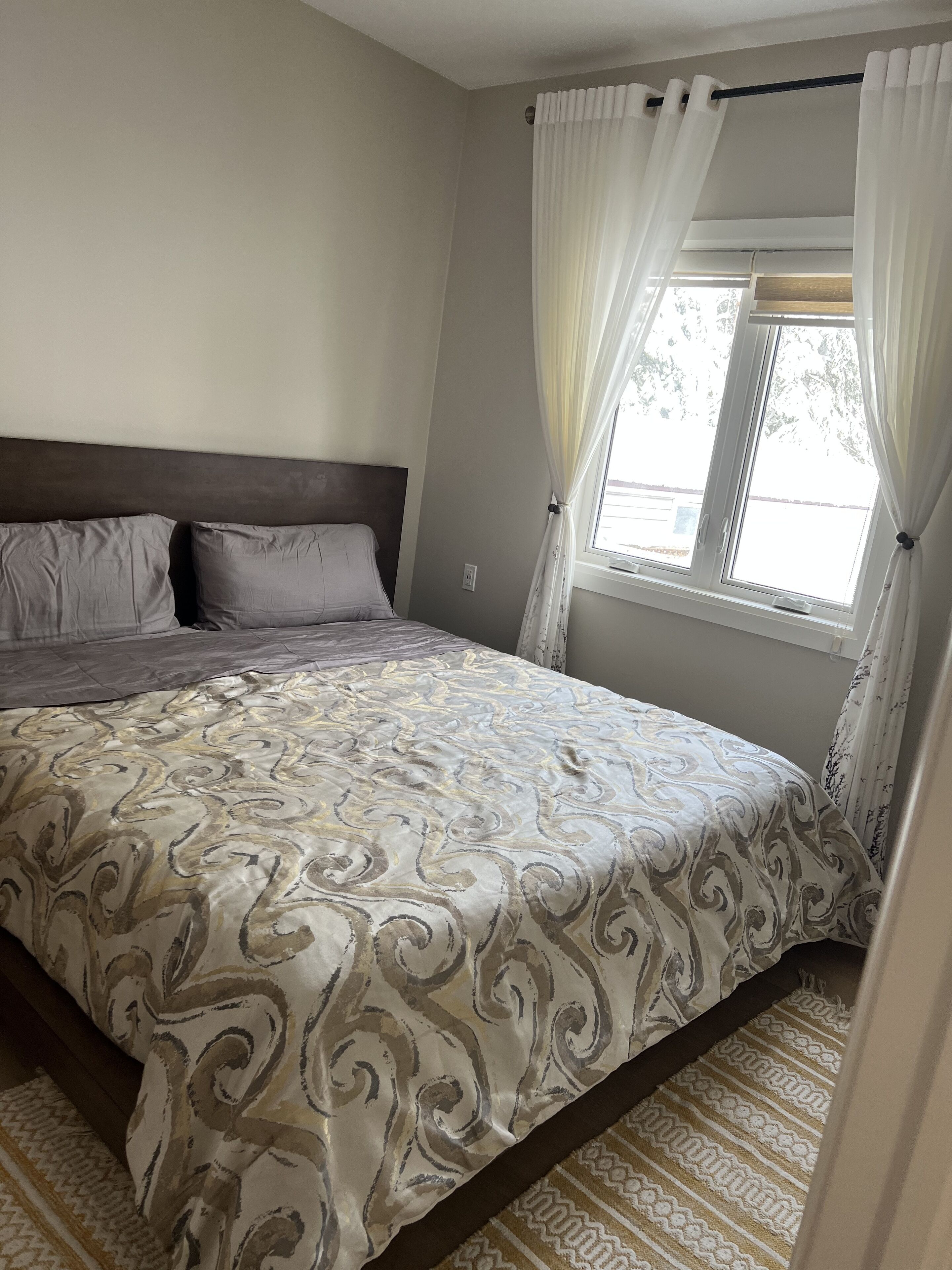 Une chambre à coucher avec un lit, des rideaux et une fenêtre.
