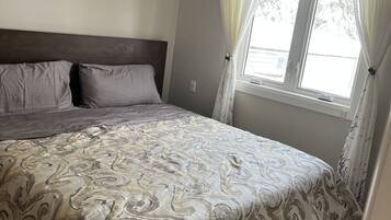 Une chambre à coucher avec un lit, des rideaux et une fenêtre.