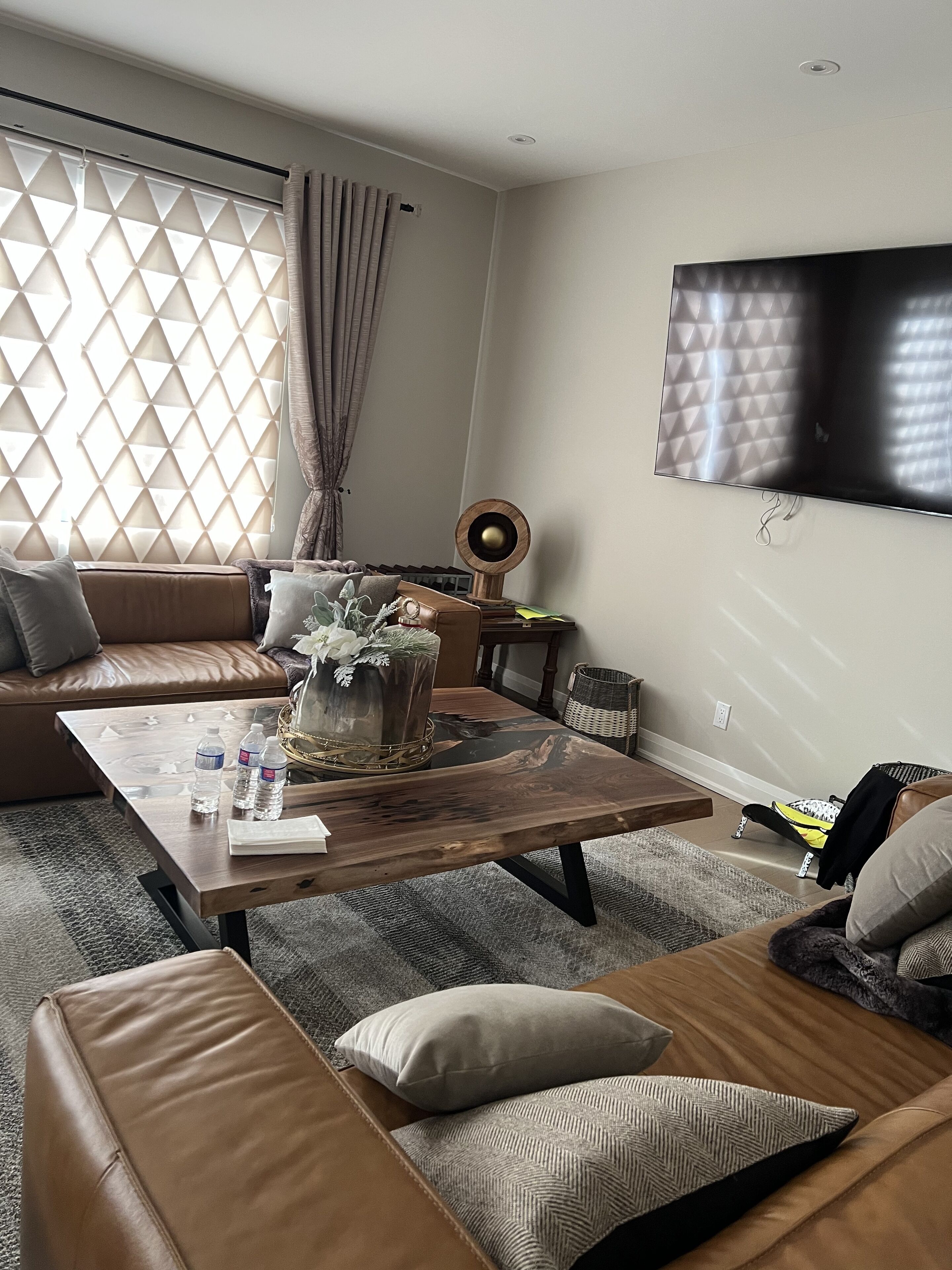 Un salon moderne avec un ensemble de canapés, une table basse et un téléviseur à écran plat fixé au mur.