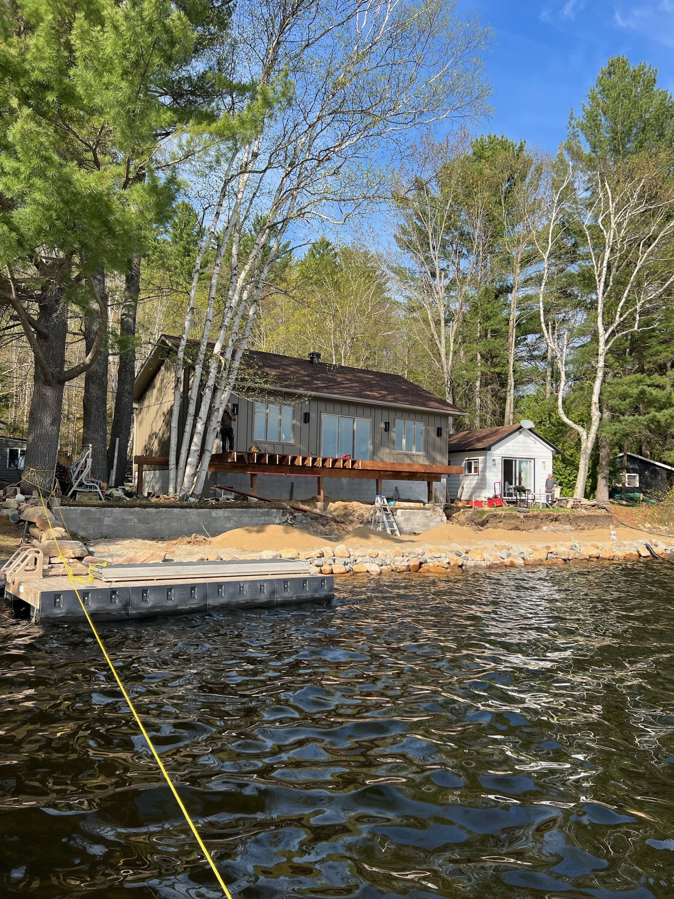 A house by a lake with a dock, surrounded by trees.
