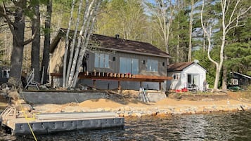 A house by a lake with a dock, surrounded by trees.