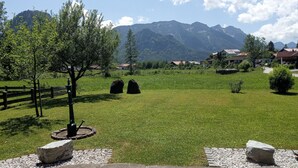 A grassy field with a wooden fence, a tree, and two stone structures. - Vacation home for up to 10 people with 4 bedrooms, 210m², large garden (Inzell)