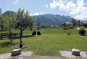 A grassy field with a wooden fence, a tree, and two stone structures.