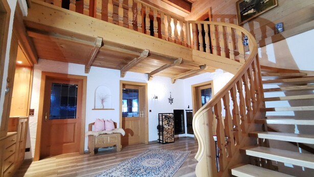 Un interior espacioso con una escalera de madera, una chimenea y un tapete grande.