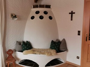 A cozy corner with a unique wall-mounted seating area featuring a white, conical design with a cross and decorative elements.