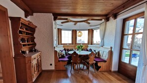 Un comedor de madera con una mesa redonda, bancos y un armario de madera.