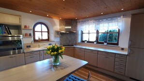 Una cocina moderna con armarios de madera, una isla central y un ventanal con plantas en macetas.