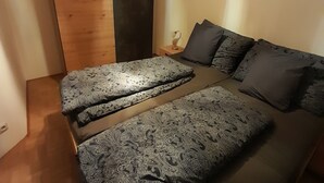 Een slaapkamer met een houten hoofdbord, een bed met beddengoed met een patroon en een nachtkastje met een lamp.
