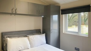 A bedroom with a bed, grey wardrobe, and a window with a view of greenery. - 1 bedroom accommodation in Kilwinning (Kilwinning)