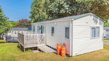 A single-story mobile home with a deck, a small porch, and propane tanks.