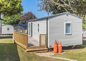 A mobile home with a deck, a window, and propane tanks.