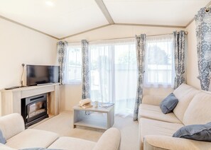 Ein Wohnzimmer mit Kamin, Sofa, Couchtisch und Fernseher.