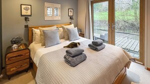 A bedroom with a large bed, a nightstand, a dresser, and a sliding glass door leading to a balcony. - 1 bedroom accommodation in Naburn, York (Naburn, York)