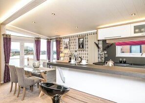 A modern kitchen with a dining area, large windows, and a view of the outdoors.