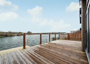 A wooden deck with a railing overlooking a body of water. - 2 bedroom accommodation in Carnforth (Carnforth)