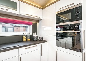 A modern kitchen with white cabinets, a black countertop, and stainless steel appliances. - 2 bedroom accommodation in Carnforth (Carnforth)