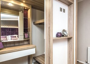 A modern bathroom with a wooden vanity, a mirror, and a shelf with decorative items. - 2 bedroom accommodation in Carnforth (Carnforth)