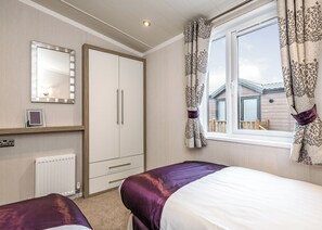 A bedroom with a wardrobe, a bed, a window with curtains, and a radiator. - 2 bedroom accommodation in Carnforth (Carnforth)