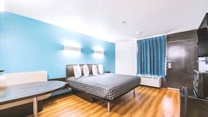 A modern hotel room with a bed, a desk, and a chair. - Blue Way Inn Fairmont (Fairmont)