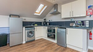 A compact kitchen with a skylight, built-in appliances, and a fire extinguisher.