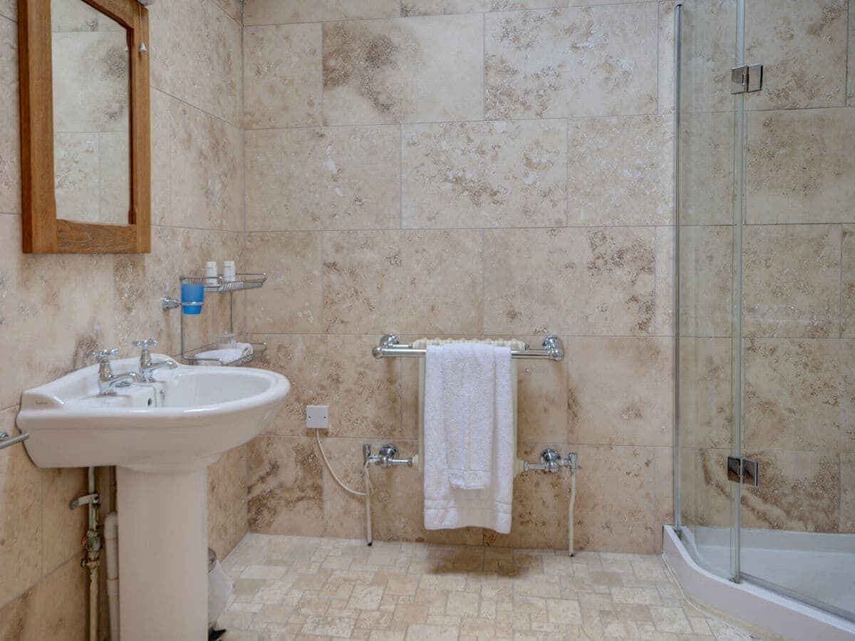 Ein Badezimmer mit Waschbecken, Spiegel, Handtuchhalter und Dusche.