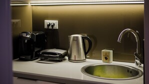 Eine Küche mit Kaffeemaschine, Wasserkocher, Toaster, einer Kapselbox und einem Spülbecken.