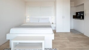 Ein modernes Schlafzimmer mit Bett, Nachttischen, einem Kleiderschrank und einer Küchenzeile.